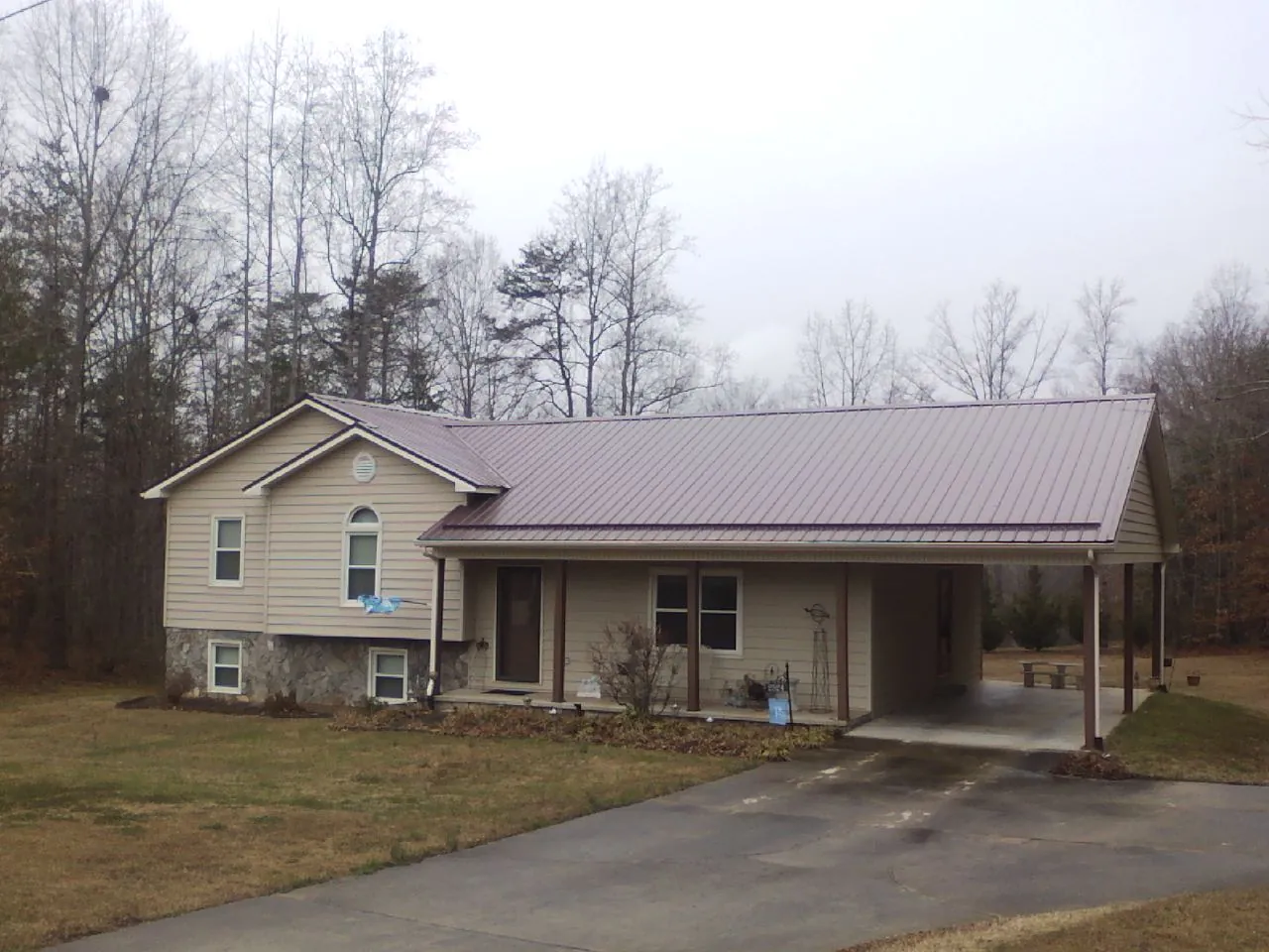 Burgundy metal roof on a tan split level home with an attached carport in Saint Anthony
