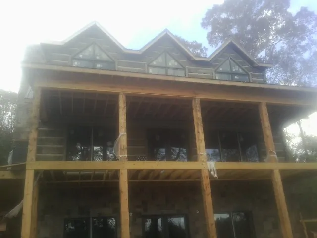 Dormers and porch framing on a large log home under construction — Roof Coating work by our crew in Saint Anthony