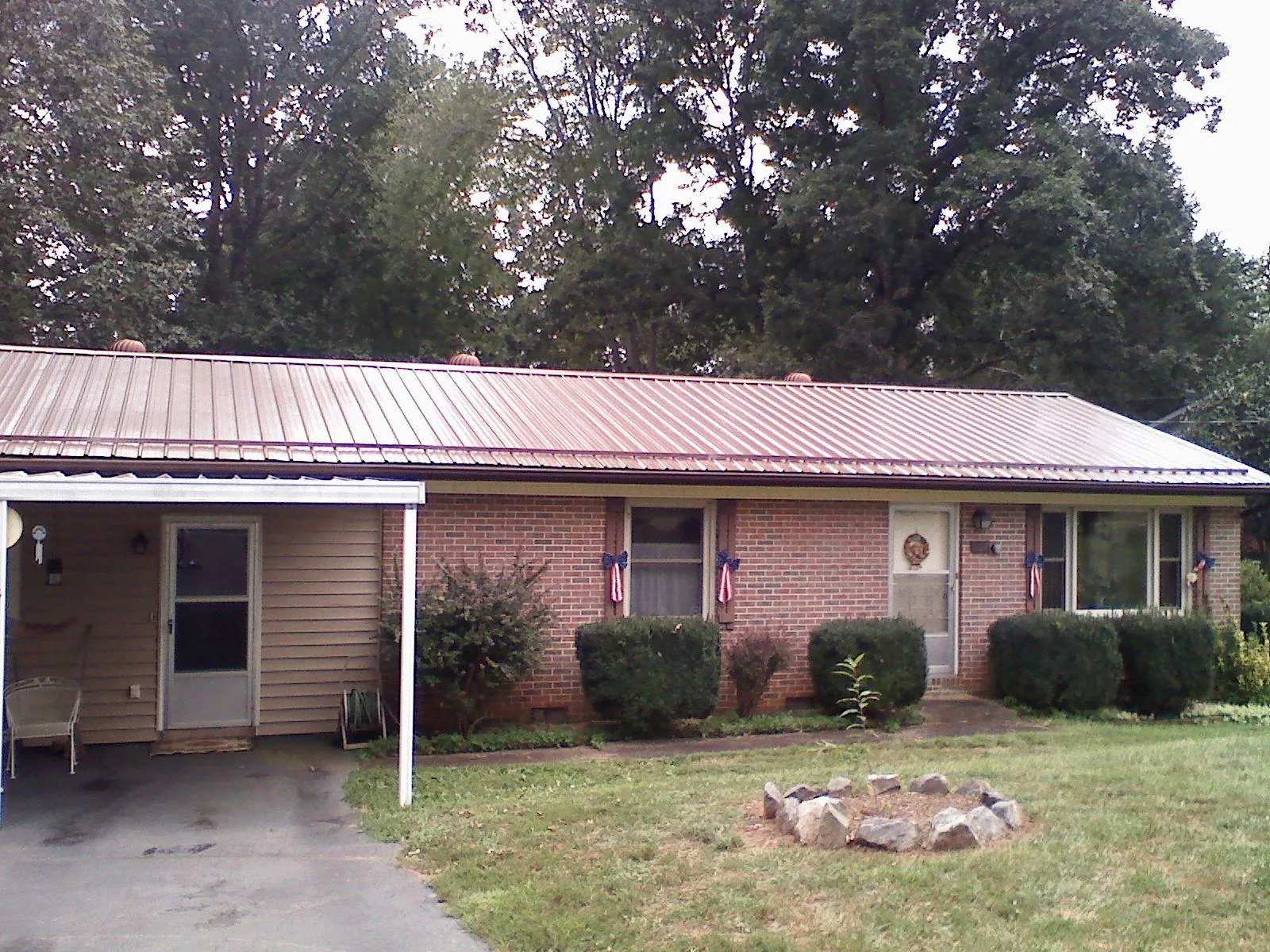 Bronze metal roof and carport on a brick ranch home — Roof Repair work by our crew in Saint Anthony