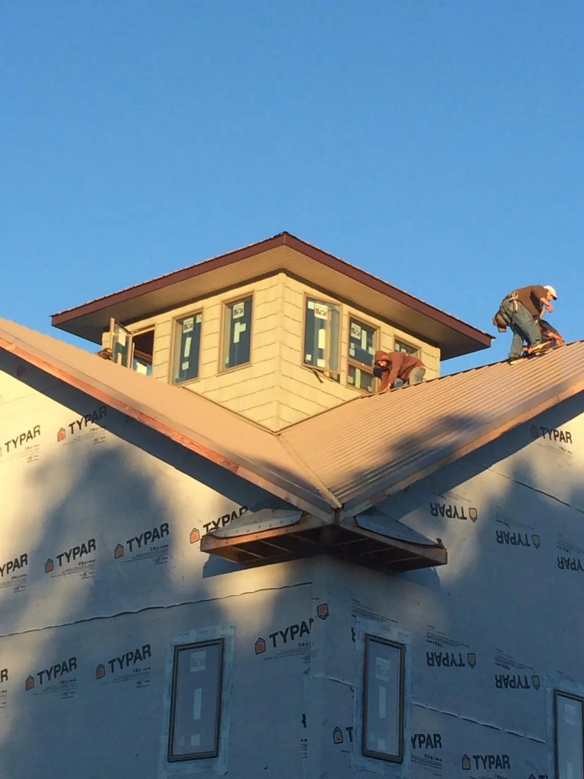 Roofers working around a rooftop cupola on a new metal roof at sunset — Roof Waterproofing in Saint Anthony by Roofing Brothers